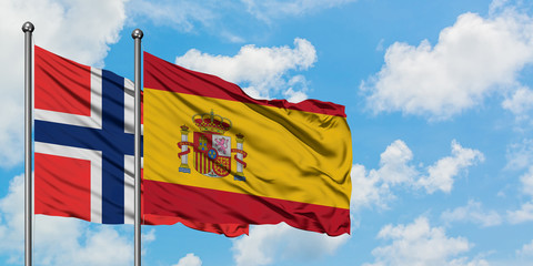Bouvet Islands and Spain flag waving in the wind against white cloudy blue sky together. Diplomacy concept, international relations.