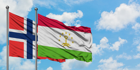 Bouvet Islands and Tajikistan flag waving in the wind against white cloudy blue sky together. Diplomacy concept, international relations.