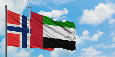 Bouvet Islands and United Arab Emirates flag waving in the wind against white cloudy blue sky together. Diplomacy concept, international relations.