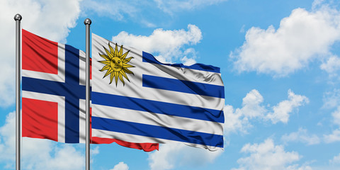 Bouvet Islands and Uruguay flag waving in the wind against white cloudy blue sky together. Diplomacy concept, international relations.