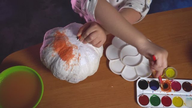 Top view on little girl who creating craft pumpking
