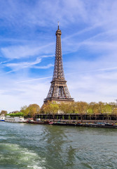 View of Eiffel Tower from Seine river in Paris France against blue sky with clouds. April 2019