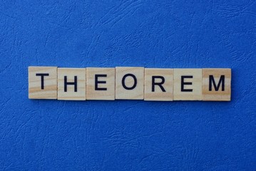 The word theorem made of brown wooden letters lies on a blue table