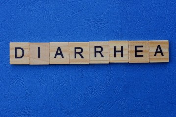 the word diarrhea from brown wooden letters lies on a blue table