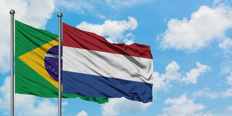Brazil and Netherlands flag waving in the wind against white cloudy blue sky together. Diplomacy concept, international relations.