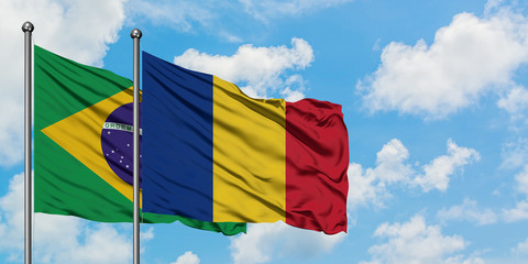 Brazil and Romania flag waving in the wind against white cloudy blue sky together. Diplomacy concept, international relations.