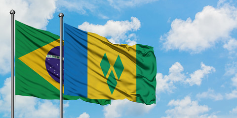 Brazil and Saint Vincent And The Grenadines flag waving in the wind against white cloudy blue sky...