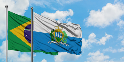 Brazil and San Marino flag waving in the wind against white cloudy blue sky together. Diplomacy concept, international relations.