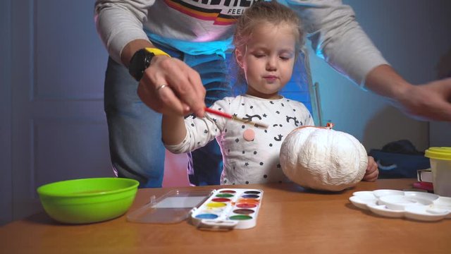 Dad helping daughter colorizing hand made craft pumpking
