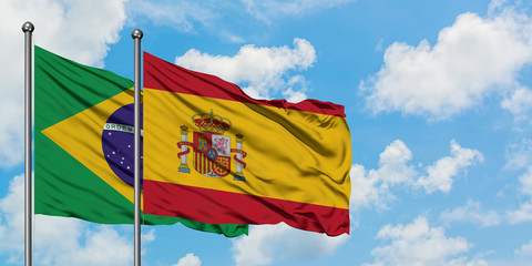 Brazil and Spain flag waving in the wind against white cloudy blue sky together. Diplomacy concept, international relations.