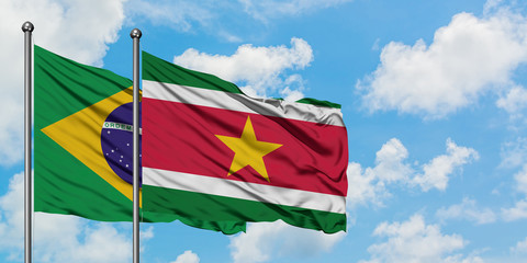 Brazil and Suriname flag waving in the wind against white cloudy blue sky together. Diplomacy concept, international relations.