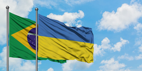 Brazil and Ukraine flag waving in the wind against white cloudy blue sky together. Diplomacy...