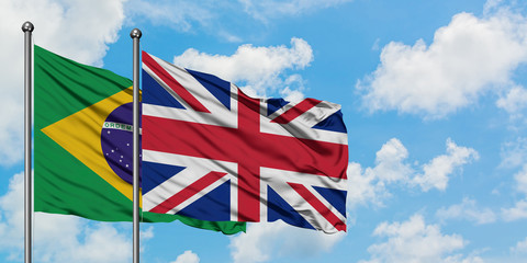 Brazil and United Kingdom flag waving in the wind against white cloudy blue sky together. Diplomacy concept, international relations.