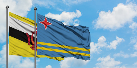 Brunei and Aruba flag waving in the wind against white cloudy blue sky together. Diplomacy concept, international relations.