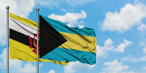 Brunei and Bahamas flag waving in the wind against white cloudy blue sky together. Diplomacy concept, international relations.