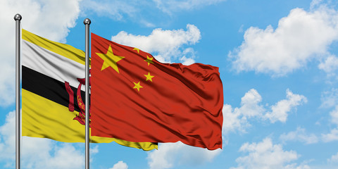 Brunei and China flag waving in the wind against white cloudy blue sky together. Diplomacy concept, international relations.