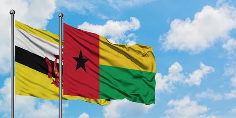 Brunei and Guinea Bissau flag waving in the wind against white cloudy blue sky together. Diplomacy concept, international relations.