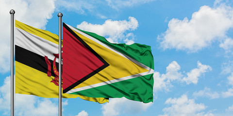 Brunei and Guyana flag waving in the wind against white cloudy blue sky together. Diplomacy concept, international relations.