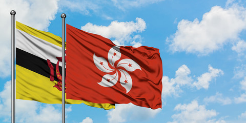 Brunei and Hong Kong flag waving in the wind against white cloudy blue sky together. Diplomacy concept, international relations.