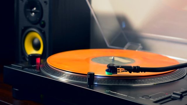 Turntable playing an orange 33 rpm vinyl record
