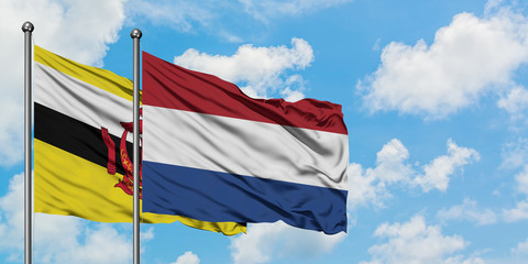 Brunei and Netherlands flag waving in the wind against white cloudy blue sky together. Diplomacy concept, international relations.