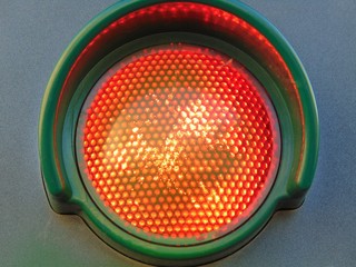 Red traffic light, isolated on gray background, close up.