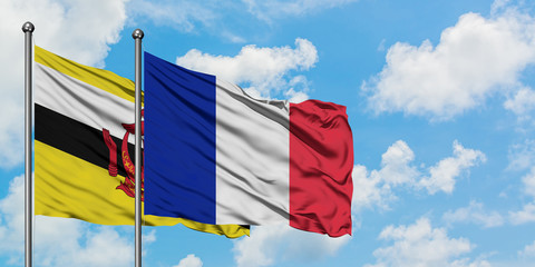 Brunei and Reunion flag waving in the wind against white cloudy blue sky together. Diplomacy concept, international relations.