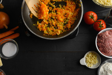 cooking Italian lasagna, preparing dressing for lasagna, Italian cuisine. Frying in a pan, with ingredients and a black background for design. Recipe book, menu, restaurant, Top view