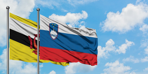 Brunei and Slovenia flag waving in the wind against white cloudy blue sky together. Diplomacy concept, international relations.