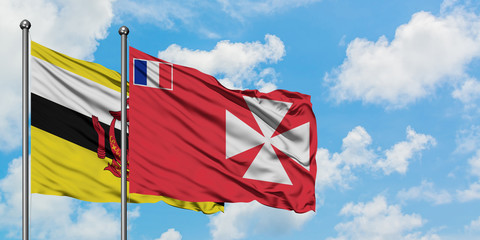 Brunei and Wallis And Futuna flag waving in the wind against white cloudy blue sky together. Diplomacy concept, international relations.