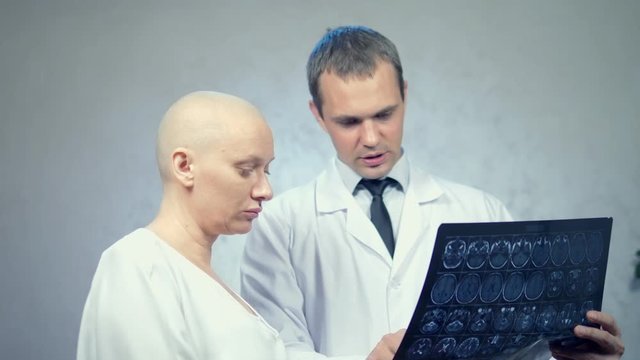 young bald woman at the doctor, consultation on the results of tomography, bad news.