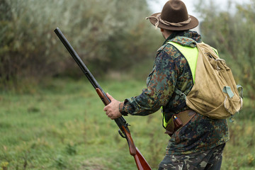 Hunting period, autumn season open. A hunter with a gun in his hands in hunting clothes in the...