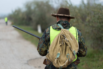 Hunting period, autumn season open. A hunter with a gun in his hands in hunting clothes in the...