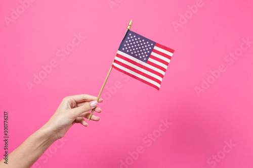 Hand holding american flag on pink
