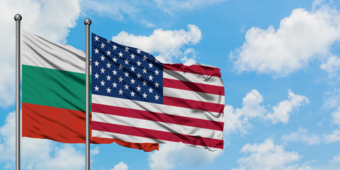 Bulgaria and United States flag waving in the wind against white cloudy blue sky together. Diplomacy concept, international relations.