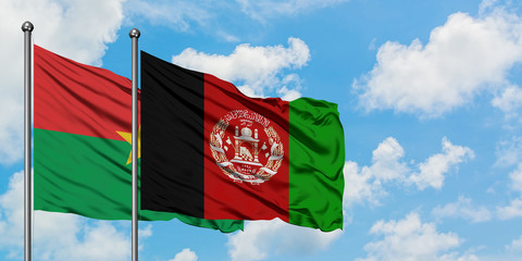 Burkina Faso and Afghanistan flag waving in the wind against white cloudy blue sky together....