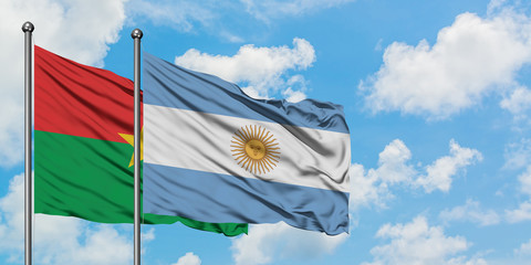 Burkina Faso and Argentina flag waving in the wind against white cloudy blue sky together. Diplomacy concept, international relations.