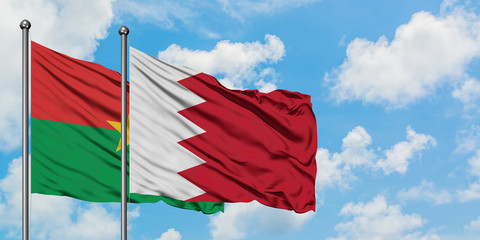 Burkina Faso and Bahrain flag waving in the wind against white cloudy blue sky together. Diplomacy concept, international relations.