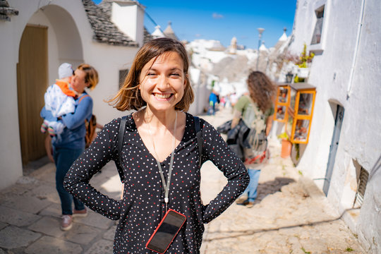Fototapeta tourist girl happy in the narrow streets of Alberobello, famous town for trulli houses in bari, Apulia, Italy