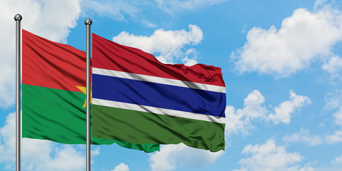 Burkina Faso and Gambia flag waving in the wind against white cloudy blue sky together. Diplomacy concept, international relations.
