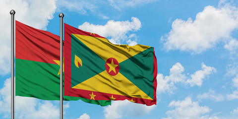 Burkina Faso and Grenada flag waving in the wind against white cloudy blue sky together. Diplomacy concept, international relations.