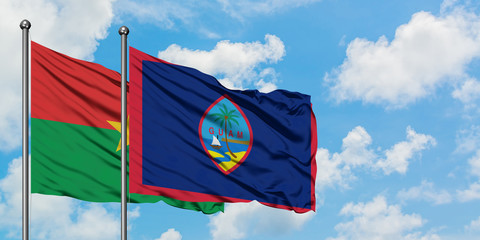 Burkina Faso and Guam flag waving in the wind against white cloudy blue sky together. Diplomacy concept, international relations.