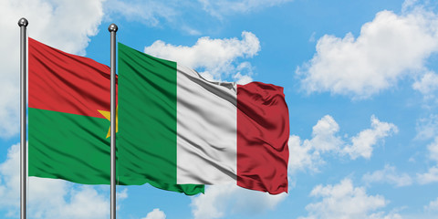 Burkina Faso and Italy flag waving in the wind against white cloudy blue sky together. Diplomacy concept, international relations.