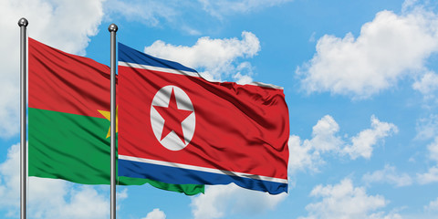 Burkina Faso and North Korea flag waving in the wind against white cloudy blue sky together. Diplomacy concept, international relations.