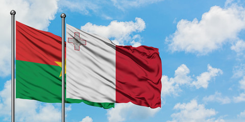 Burkina Faso and Malta flag waving in the wind against white cloudy blue sky together. Diplomacy concept, international relations.