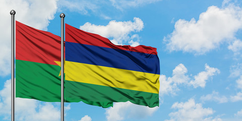 Burkina Faso and Mauritius flag waving in the wind against white cloudy blue sky together. Diplomacy concept, international relations.
