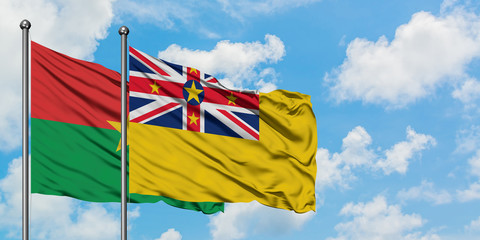 Burkina Faso and Niue flag waving in the wind against white cloudy blue sky together. Diplomacy concept, international relations.