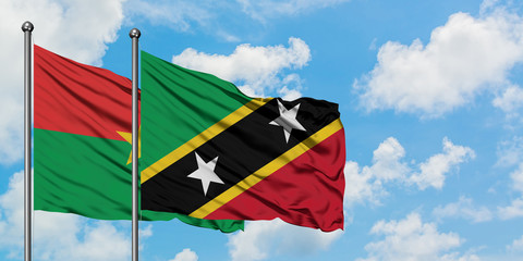 Burkina Faso and Saint Kitts And Nevis flag waving in the wind against white cloudy blue sky together. Diplomacy concept, international relations.