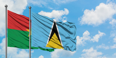 Burkina Faso and Saint Lucia flag waving in the wind against white cloudy blue sky together. Diplomacy concept, international relations.