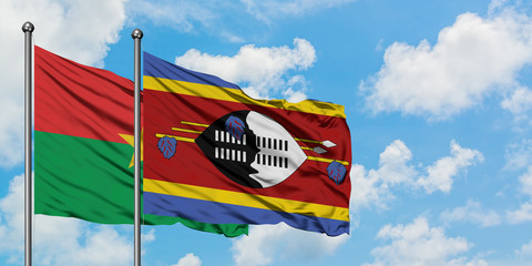 Burkina Faso and Swaziland flag waving in the wind against white cloudy blue sky together. Diplomacy concept, international relations.